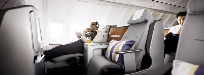 Lufthansa Business Class - A man wearing headphones is sitting in the 747-8 Business Class
