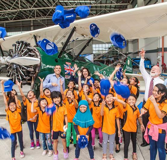 Female aviator Tracey Curtis-Taylor (background middle) inspires young girls during her Singapore stopover, as part of her U.K. to Australia expedition on a 1942 Boeing Stearman biplane.