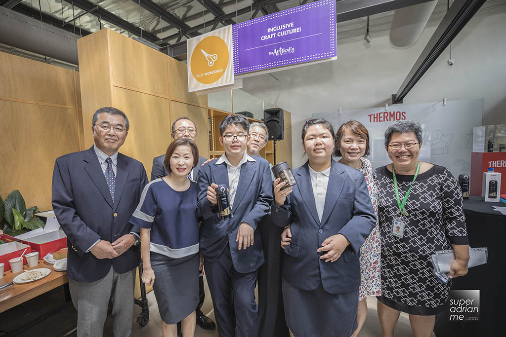 13 year old Jonathan Cai and his Thermos Singapore Exclusive Local Design One-Push Tumbler and 15-year old Grace Ong with her Thermos Singapore Exclusive Local Design Food Jar posing with parent, Thermos executives and Pathlight executives.