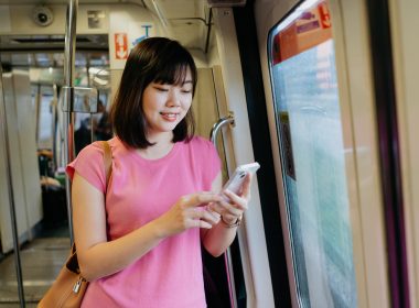 Young asian woman using smartphone while riding the train