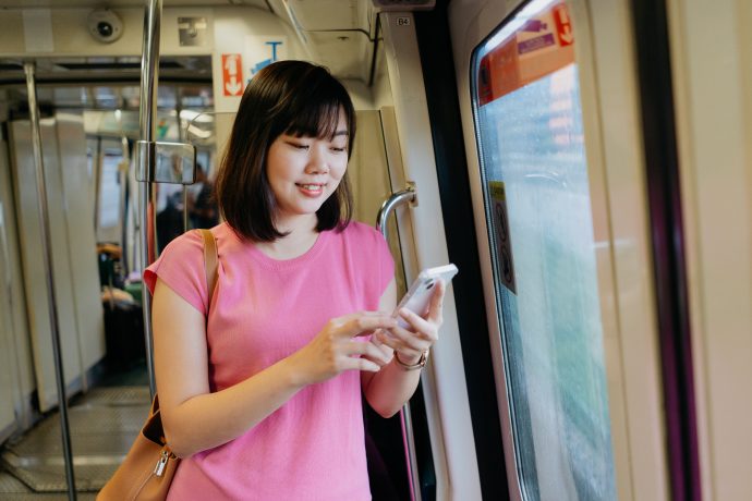 Young asian woman using smartphone while riding the train | SUPERADRIANME.com Young asian woman using smartphone while riding the train