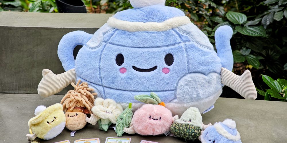 CHAGEE's six hand-holding Bes-Tea Brew Crew characters with the Brew Pot Pillow Plush. (SUPERADRIANME photo) | SUPERADRIANME.com CHAGEE's six Bes-Tea Brew Crew plushies holding hands in front of a large blue Brew Pot Pillow Plush