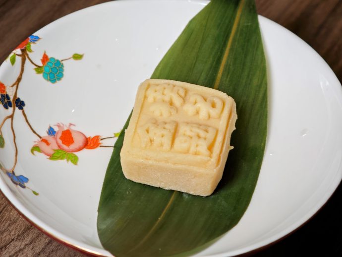 Square mung bean cake with salted egg yolk served on a green leaf | SUPERADRIANME.com Square mung bean cake with salted egg yolk served on a green leaf